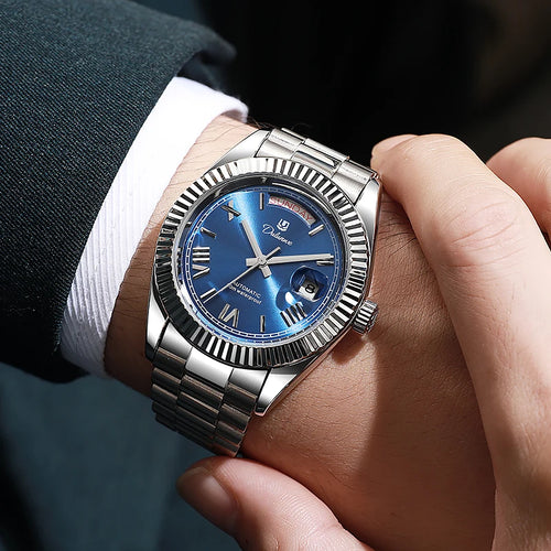 Luxury silver wristwatch with blue dial, Roman numerals, and date display on man's wrist